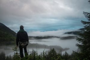 Pedestrian walking in Alaska overlooking a foggy landscape